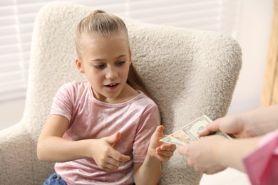 Photo of Mother giving her daughter pocket money at home, closeup