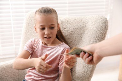 Photo of Mother giving her daughter pocket money at home, closeup