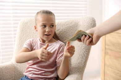 Photo of Mother giving her daughter pocket money at home, closeup