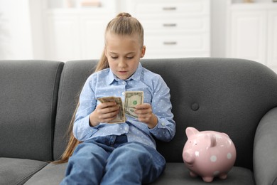 Photo of Little girl with pocket money on sofa at home