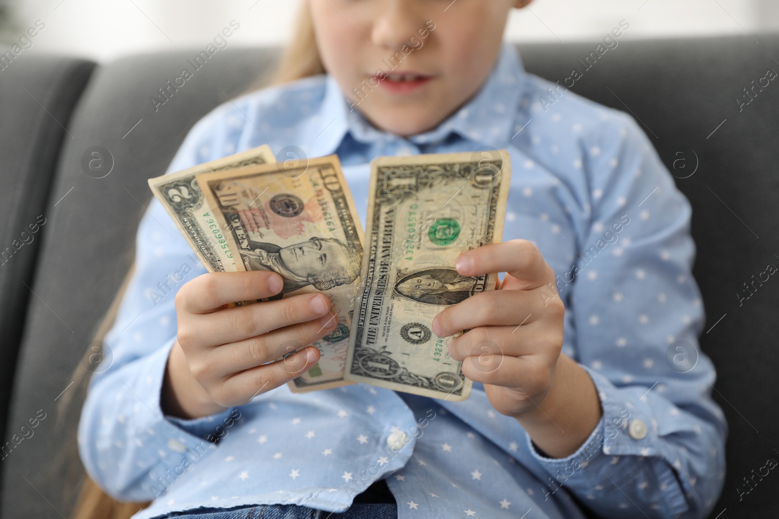 Photo of Little girl with pocket money on sofa at home, closeup