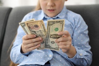 Photo of Little girl with pocket money on sofa at home, closeup
