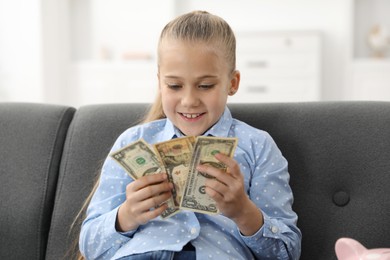 Photo of Little girl with pocket money on sofa at home