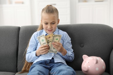 Photo of Little girl with pocket money on sofa at home