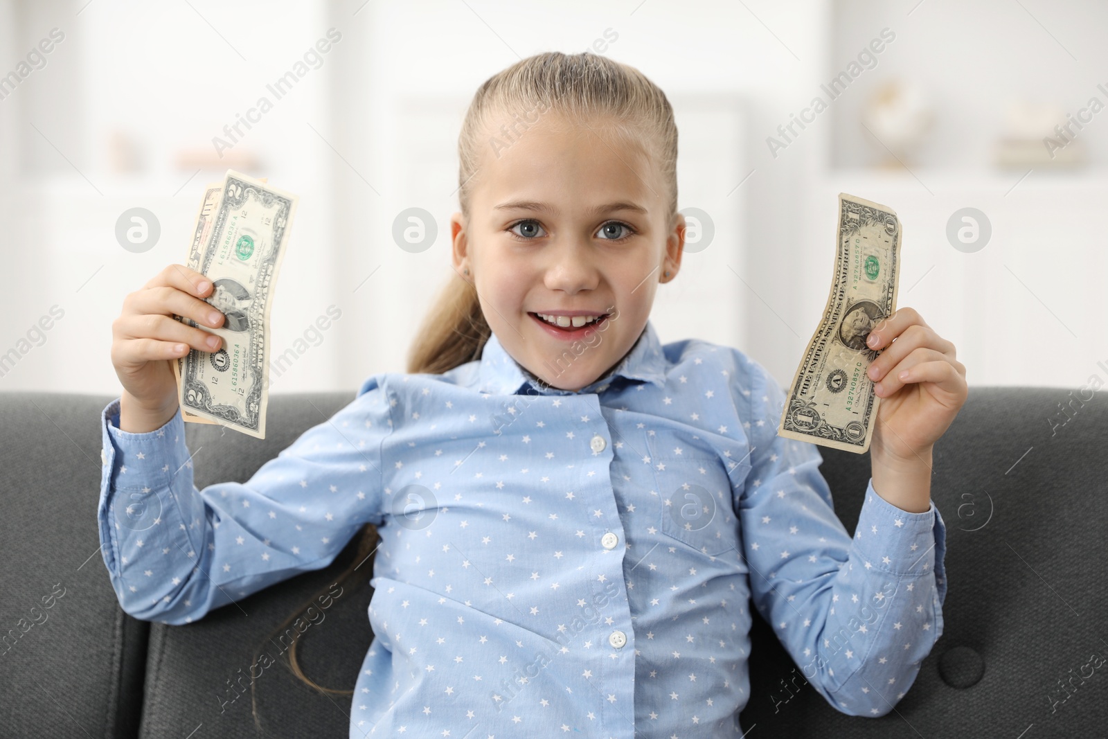 Photo of Little girl with pocket money on sofa at home