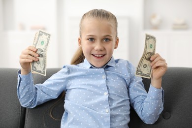 Photo of Little girl with pocket money on sofa at home