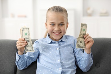 Photo of Little girl with pocket money on sofa at home