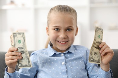 Photo of Little girl with pocket money on sofa at home