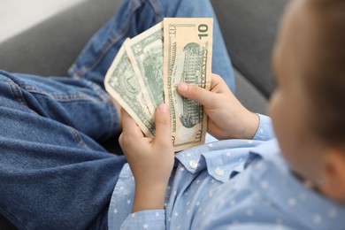 Photo of Little girl with pocket money on sofa, above view