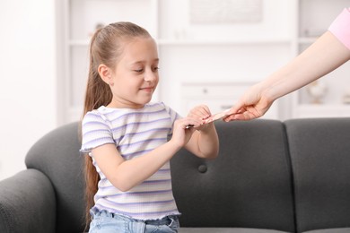 Photo of Mother giving her daughter pocket money at home, closeup