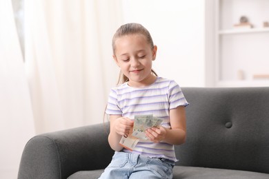 Photo of Little girl with pocket money on sofa at home
