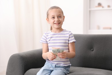Photo of Little girl with pocket money on sofa at home
