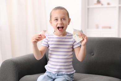 Photo of Little girl with pocket money on sofa at home