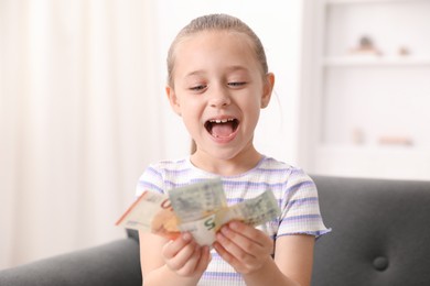 Photo of Little girl with pocket money on sofa at home