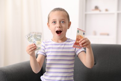 Photo of Little girl with pocket money on sofa at home