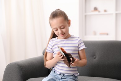 Photo of Little girl with pocket money on sofa at home