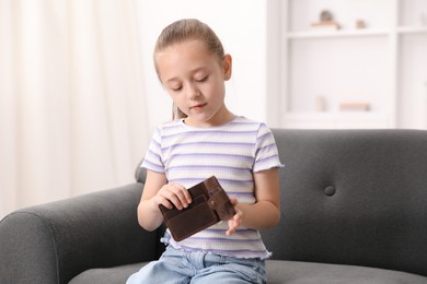 Photo of Pocket money. Little girl with purse on sofa at home