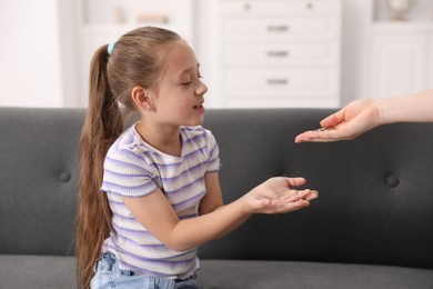 Photo of Mother giving her daughter pocket money at home, closeup