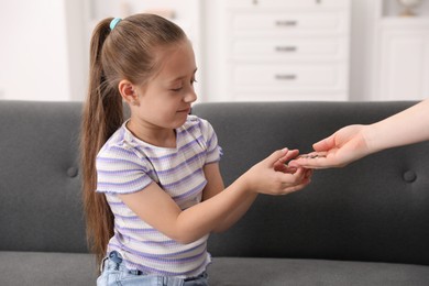 Photo of Mother giving her daughter pocket money at home, closeup