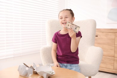 Photo of Little girl with pocket money in armchair at home, space for text