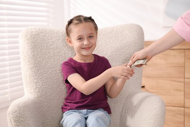 Photo of Mother giving her daughter pocket money at home, closeup