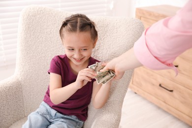 Photo of Mother giving her daughter pocket money at home, closeup