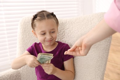 Photo of Mother giving her daughter pocket money at home, closeup