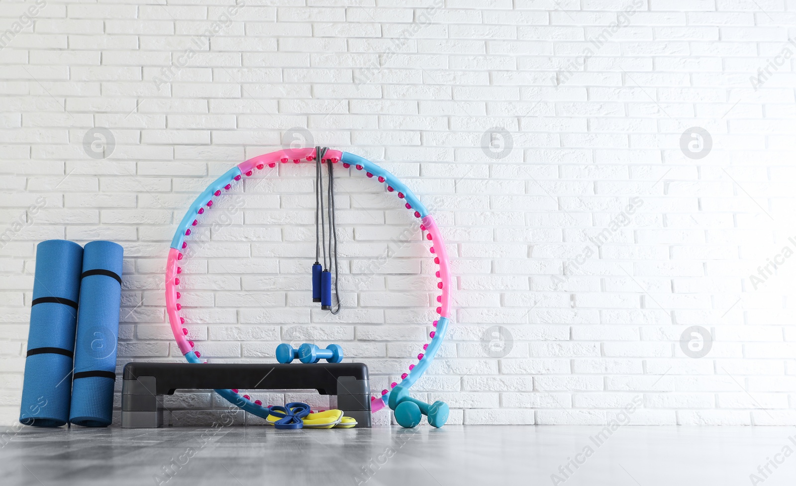 Photo of Different sports equipment near white brick wall in gym. Space for text