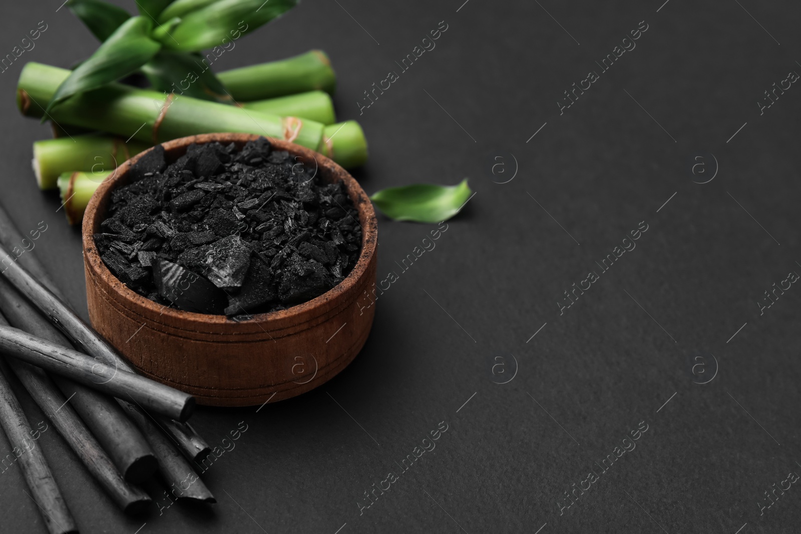 Photo of Fresh bamboo and charcoal on black background, space for text