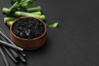 Photo of Fresh bamboo and charcoal on black background, space for text