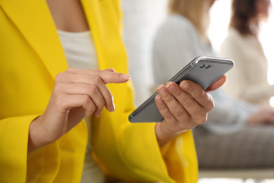 Photo of Young woman using modern smartphone indoors, closeup