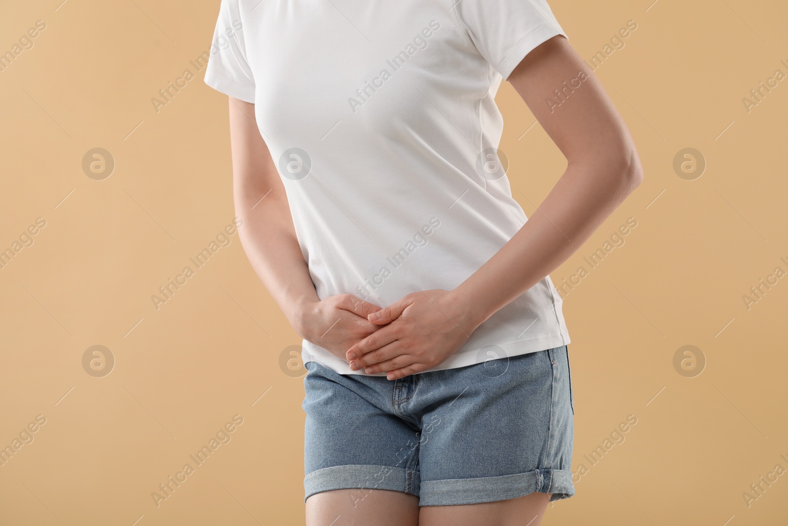 Photo of Woman suffering from cystitis on beige background, closeup