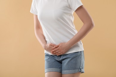 Photo of Woman suffering from cystitis on beige background, closeup