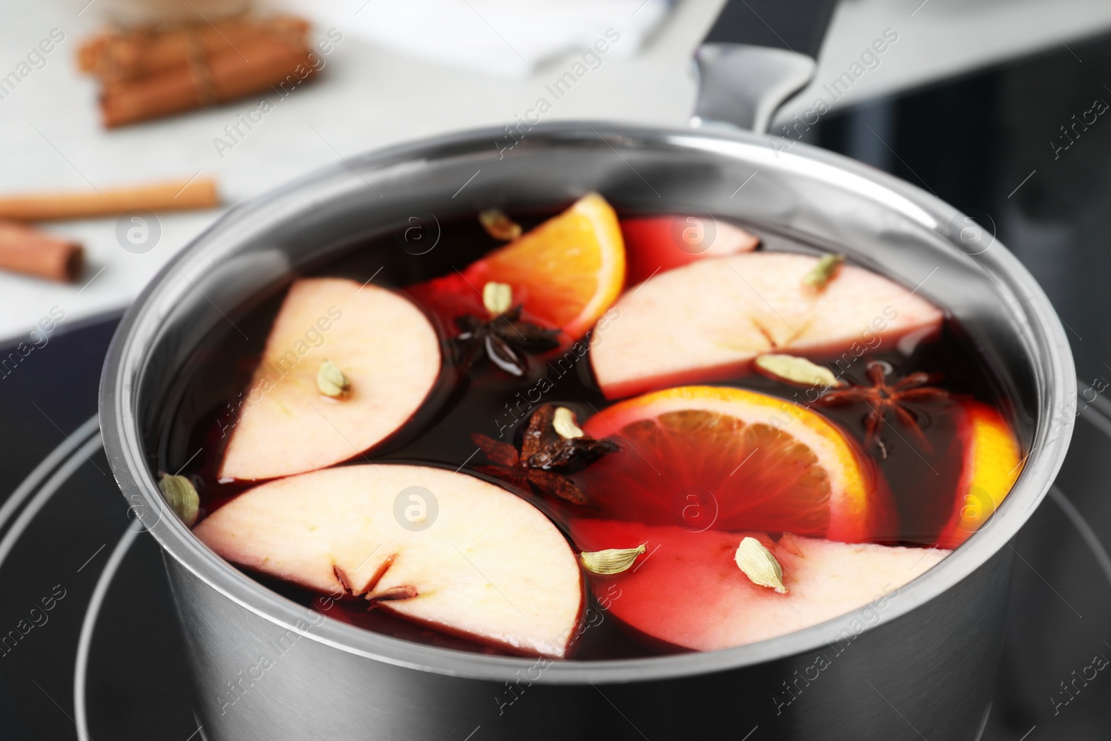 Photo of Delicious hot mulled wine on stove, closeup