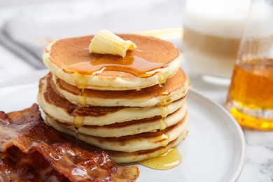 Photo of Delicious pancakes with maple syrup, butter and fried bacon on table, closeup