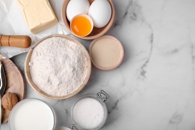 Photo of Bowl of flour and other ingredients in white marble table, flat lay. Space for text