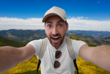 Image of Smiling man taking selfie in beautiful mountains