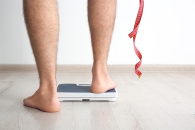 Photo of Overweight man measuring his weight indoors