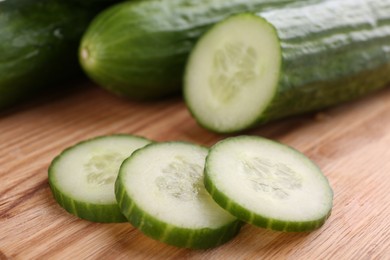 Photo of Fresh cucumbers on wooden cutting board, closeup