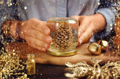 Image of Woman making snow globe at wooden table, closeup