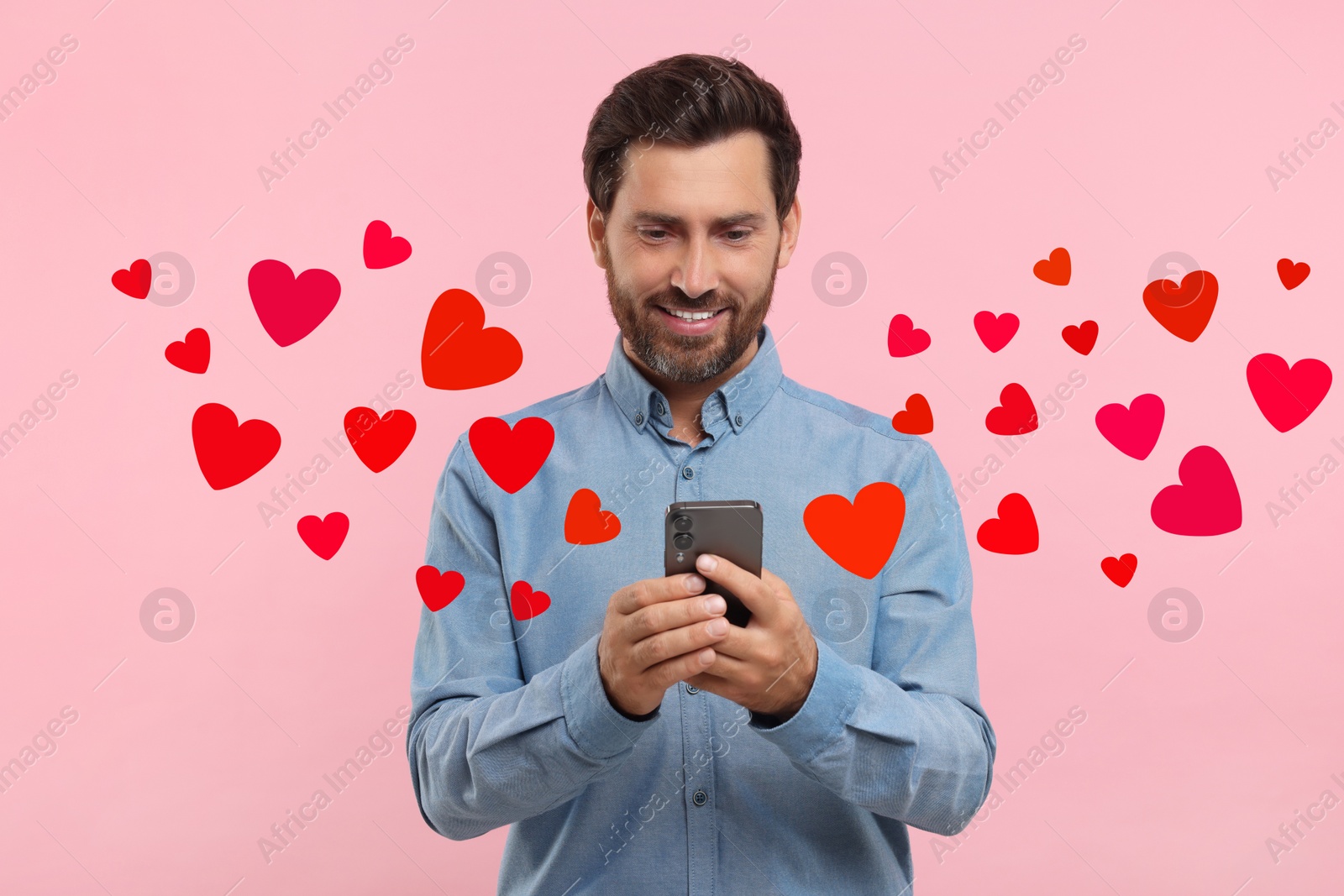 Image of Long distance love. Man chatting with sweetheart via smartphone on pink background. Hearts flying out of device and swirling around him