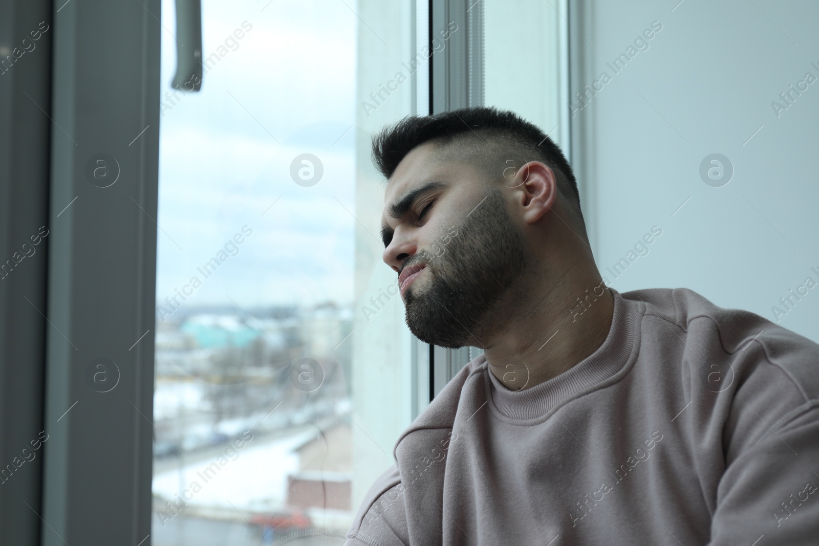 Photo of Portrait of sad man near window at home