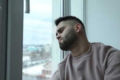 Photo of Portrait of sad man near window at home