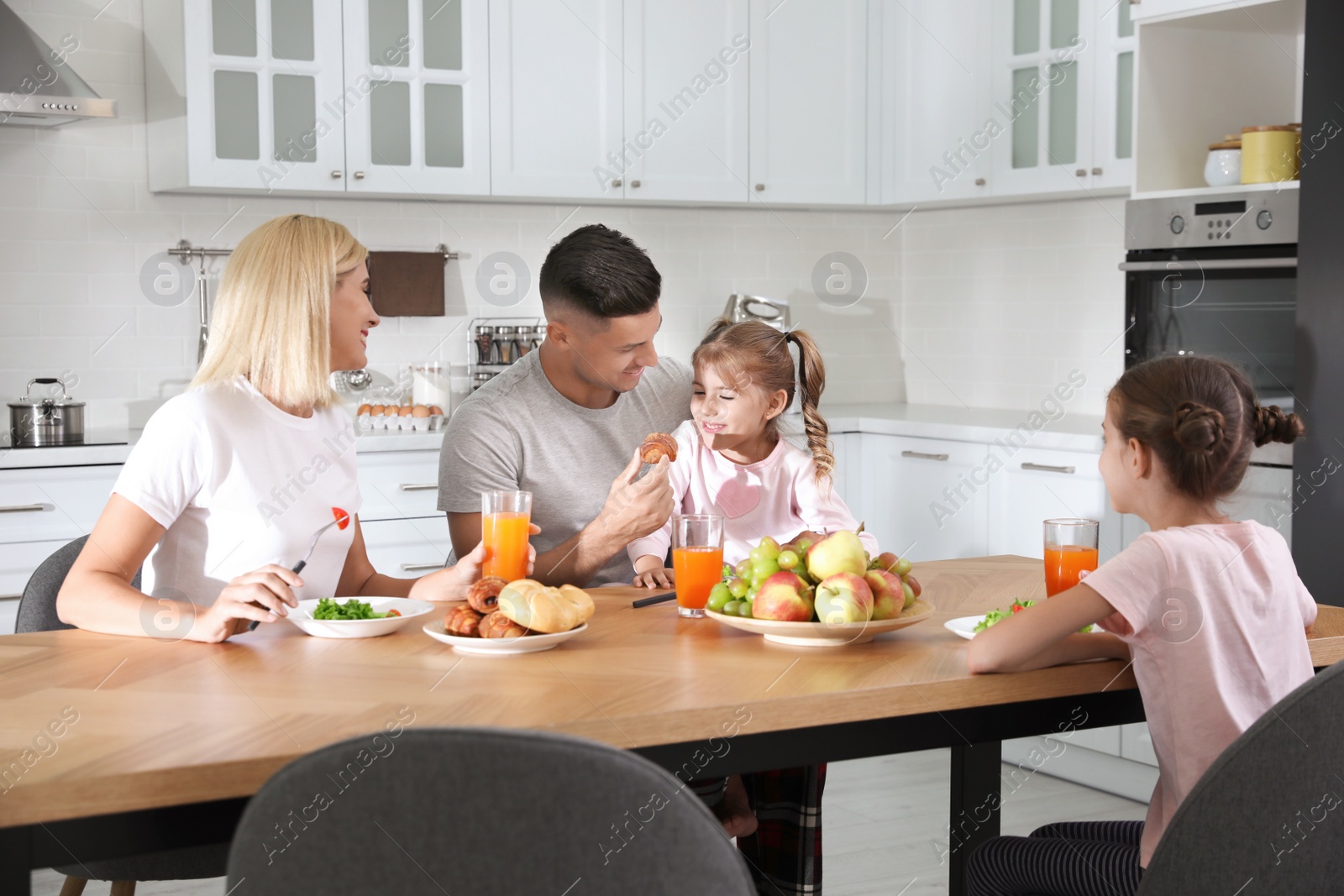 Photo of Happy family having breakfast together at table in modern kitchen