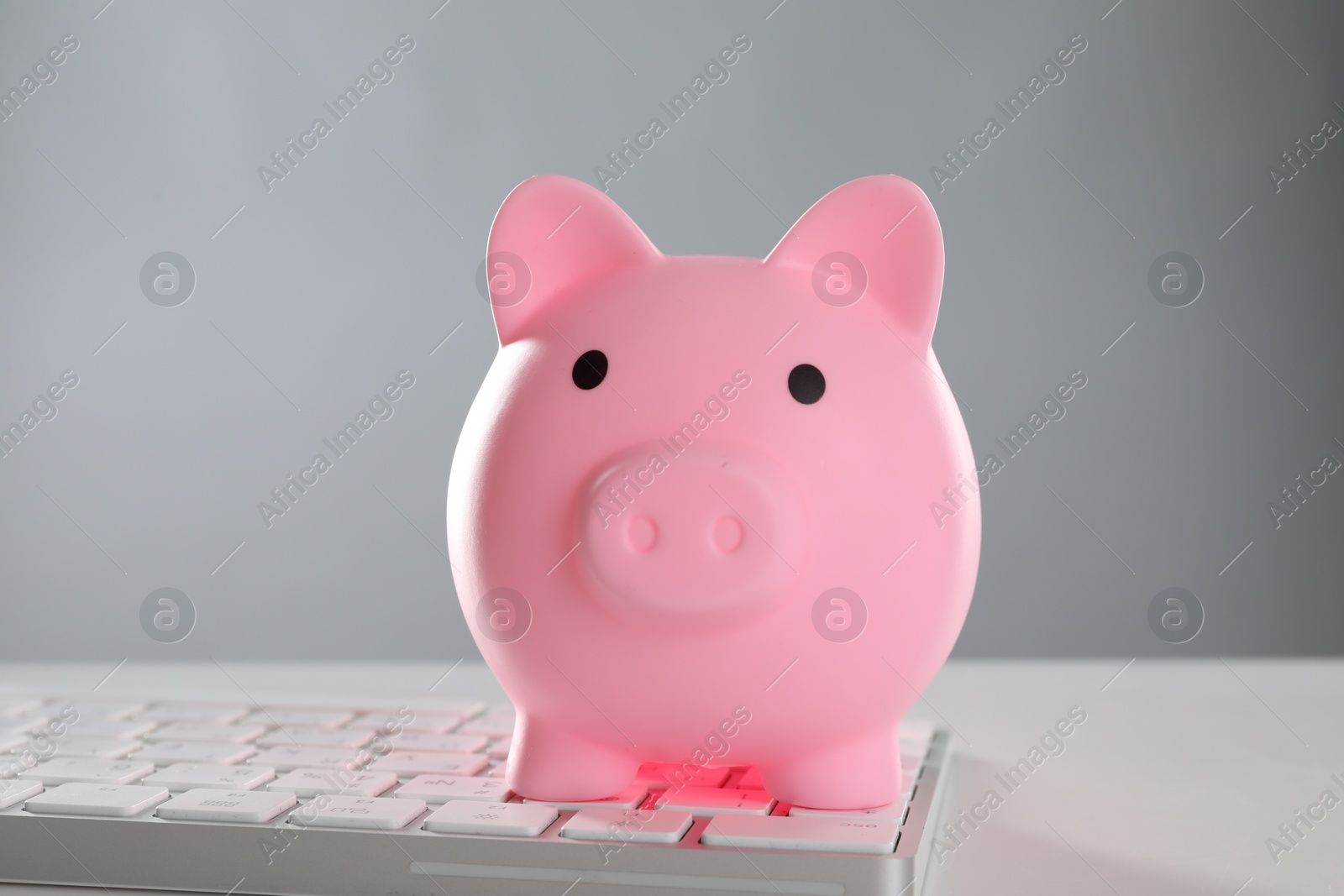 Photo of Pink piggy bank and keyboard on white table