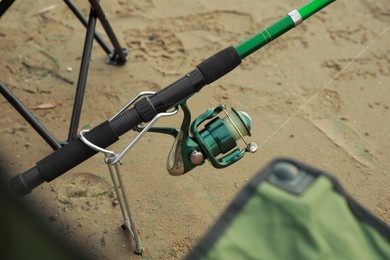 Photo of Fishing rod with reel on sand, closeup