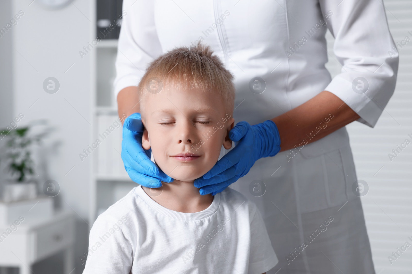 Photo of Endocrinologist examining boy's thyroid gland at hospital, closeup