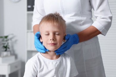 Endocrinologist examining boy's thyroid gland at hospital, closeup
