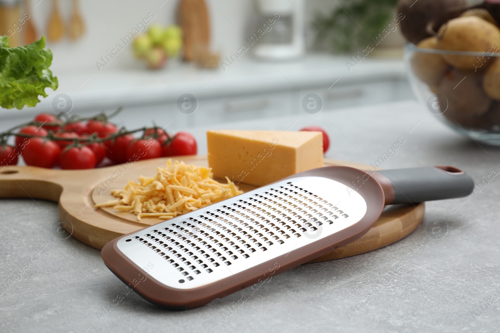 Photo of Grater and cheese on grey table in kitchen