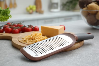 Grater and cheese on grey table in kitchen